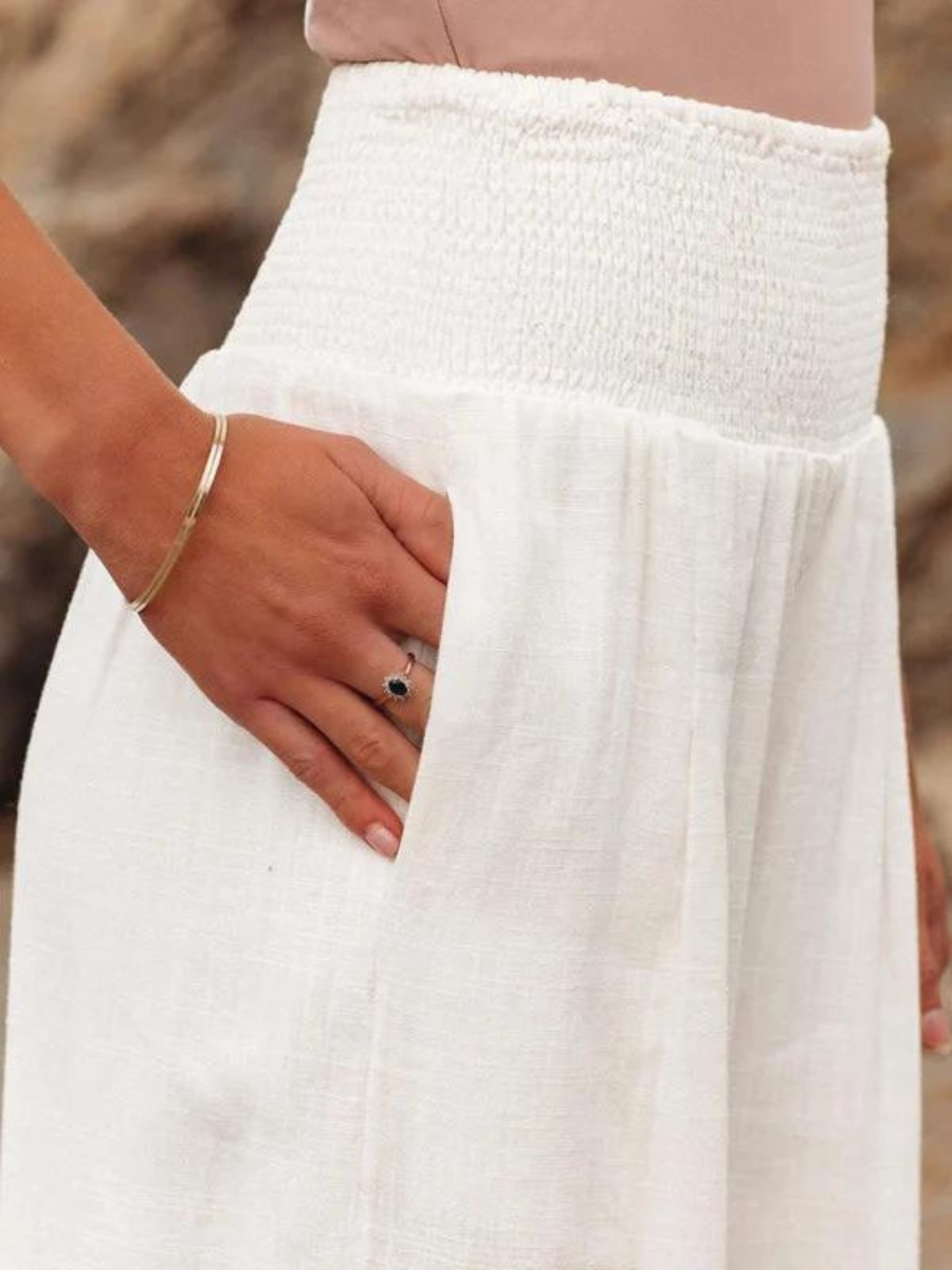 A woman walking by the sea in wide-leg beach pants with a relaxed, breezy summer look.