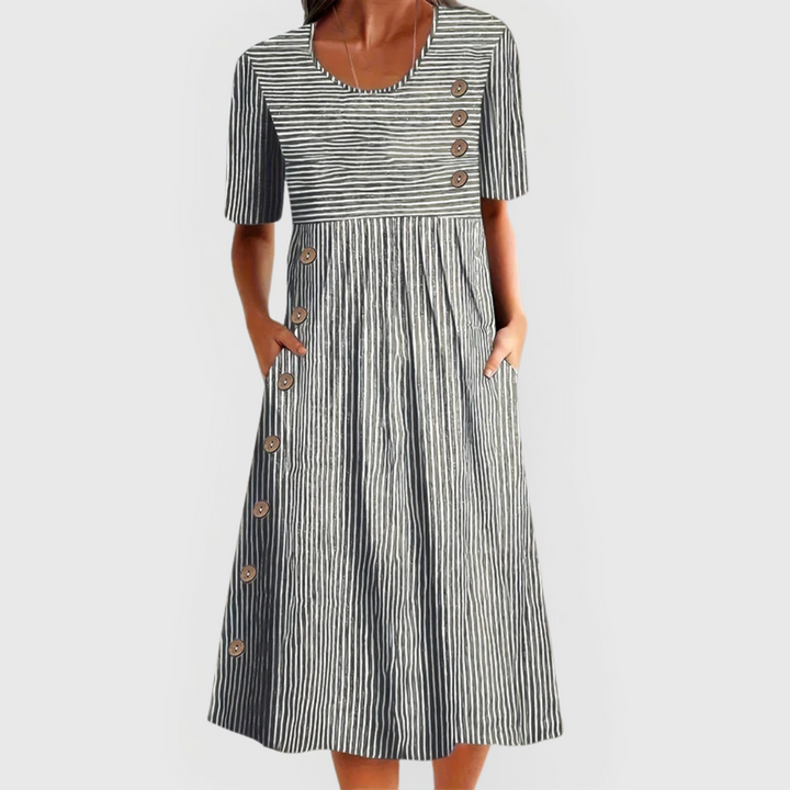 A woman wearing the Helen striped midi dress with button details, standing outdoors on a bright day.