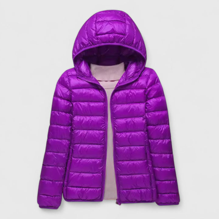 A woman wearing a lightweight padded jacket with a hood, outdoors on a cool day