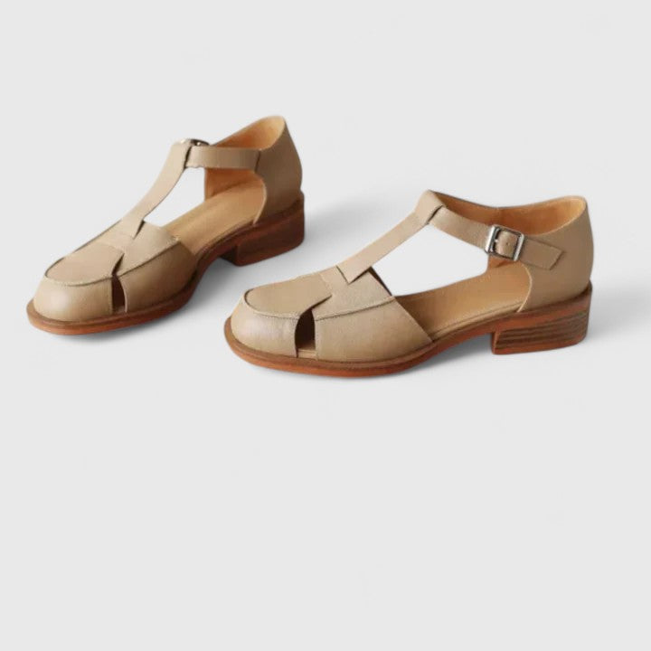 Woman wearing beige strapped Mary Jane sandals on a sunny terrace.