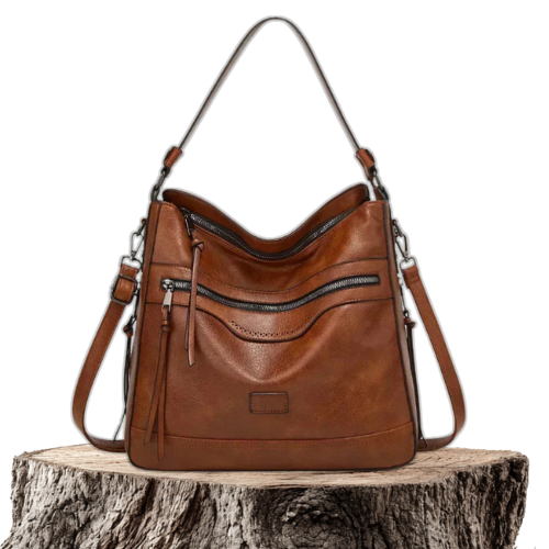 A soft brown vintage shoulder bag with zip pockets and tassel pulls, carried on the shoulder in town.