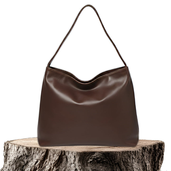 A woman wearing a glossy taupe shoulder bag over her shoulder at an evening occasion.