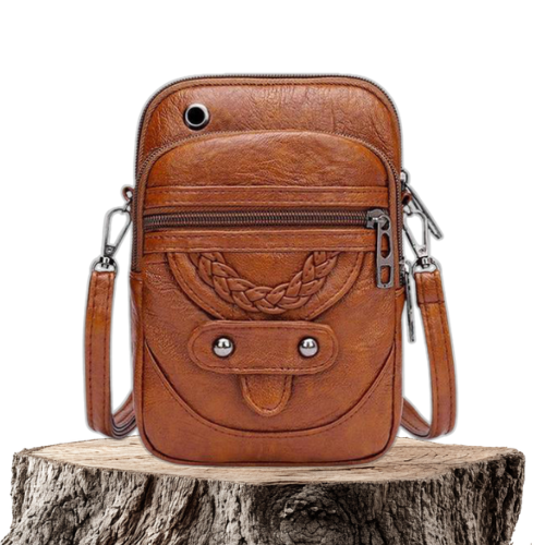 A small brown crossbody bag with a plaited front detail and zip pockets on a wooden stump.