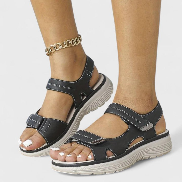 A woman walking gracefully in blue support sandals with a broad, cushioned footbed.