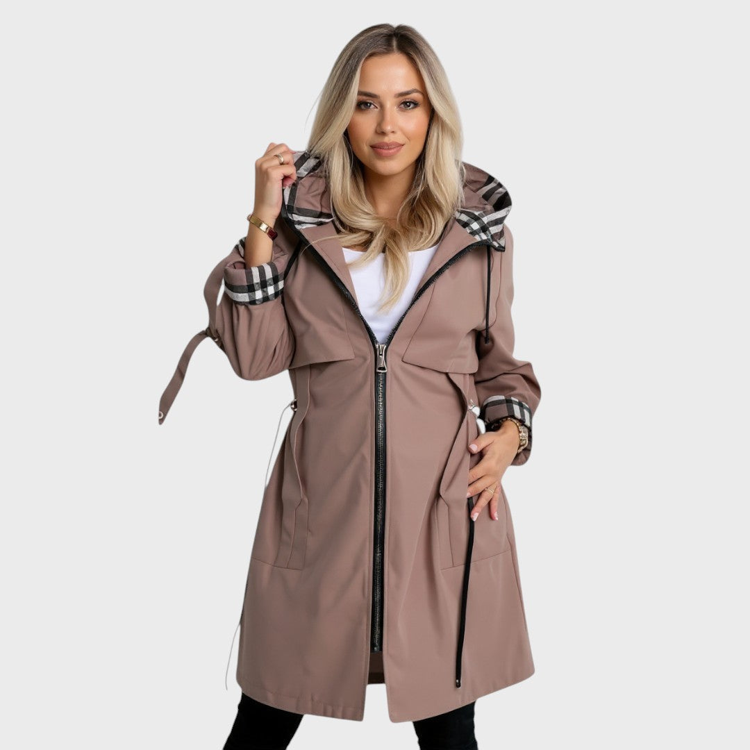 A woman wearing a waisted zip-up coat, standing outdoors on a cold day