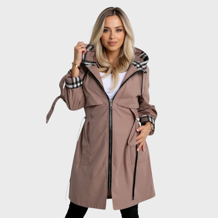 A woman wearing a waisted zip-up coat, standing outdoors on a cold day