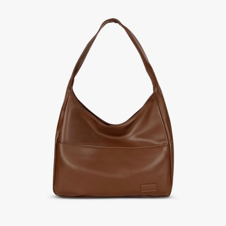 A woman wearing an elegant shoulder bag at her hip while out for the day.