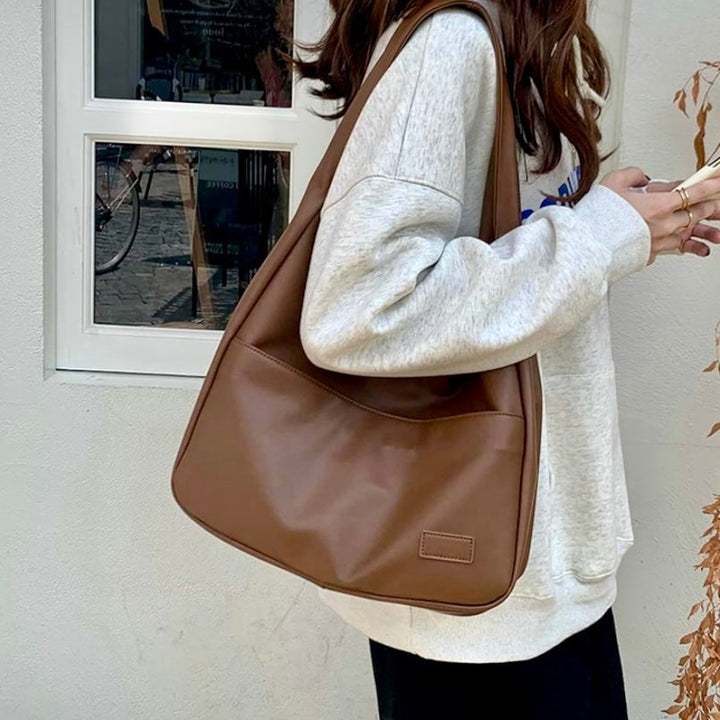 A woman wearing an elegant shoulder bag at her hip while out for the day.