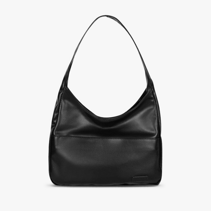 A woman wearing an elegant shoulder bag at her hip while out for the day.