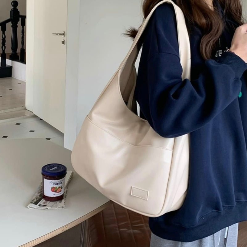 A woman wearing an elegant shoulder bag at her hip while out for the day.