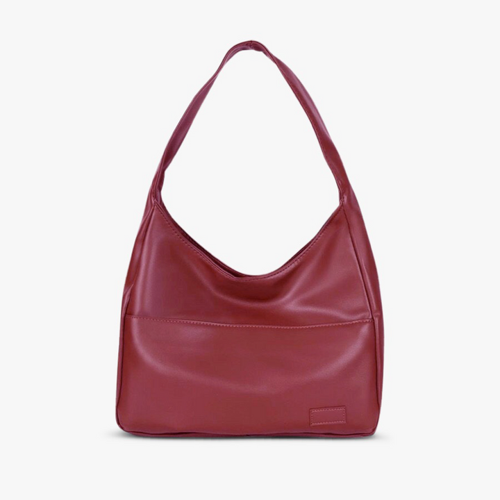 A woman wearing an elegant shoulder bag at her hip while out for the day.