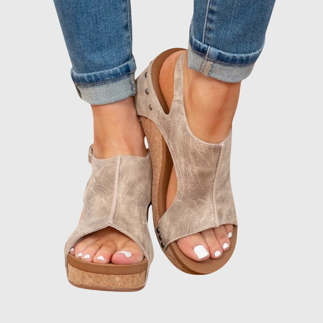 A woman in taupe wedge sandals with an open front, out shopping on a warm day.