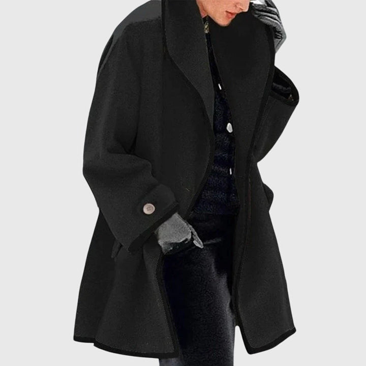 A woman wearing a blue swing-cut jacket with a black contrast trim