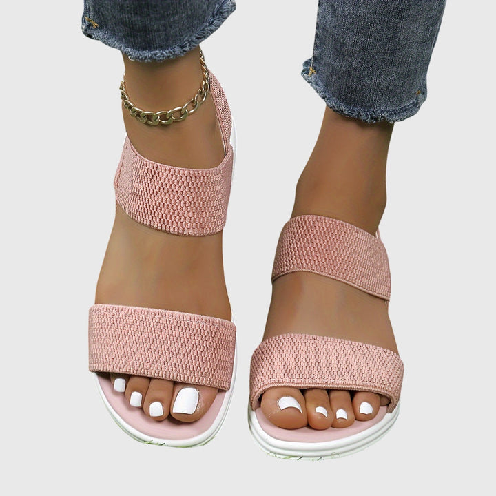 Black open-toe everyday sandals with wide stretch straps and a thick cushioned sole.