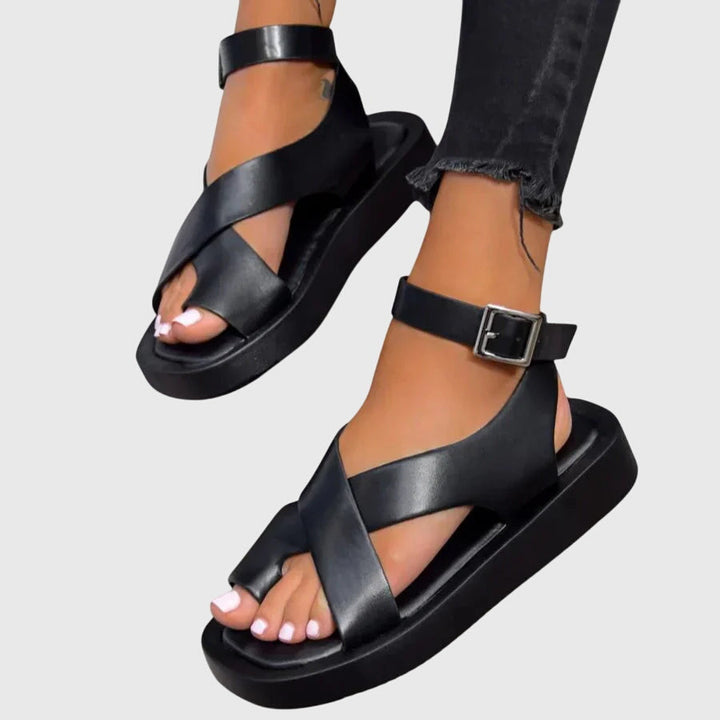 A woman in black chunky platform sandals with an ankle strap, standing confidently, feet cushioned and supported.