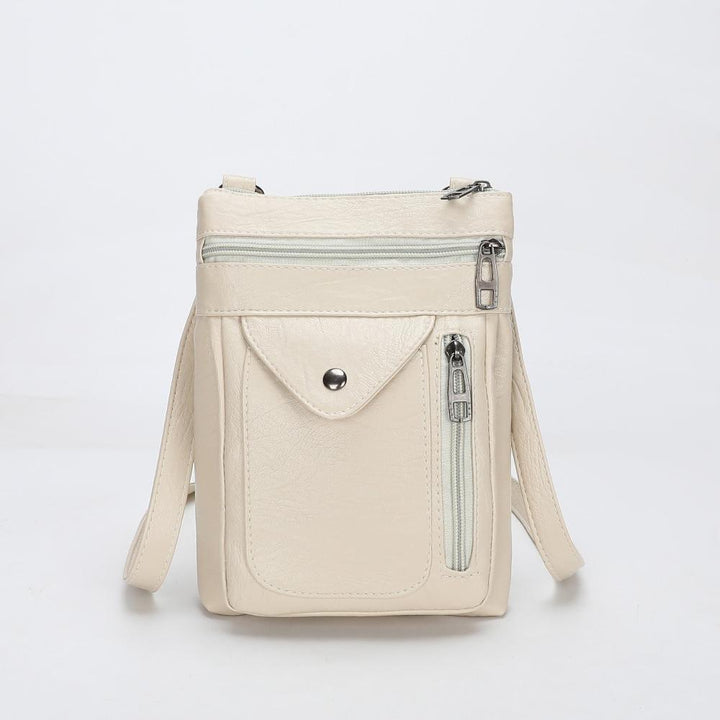 A woman wearing a compact vintage crossbody bag across her body while walking through town.