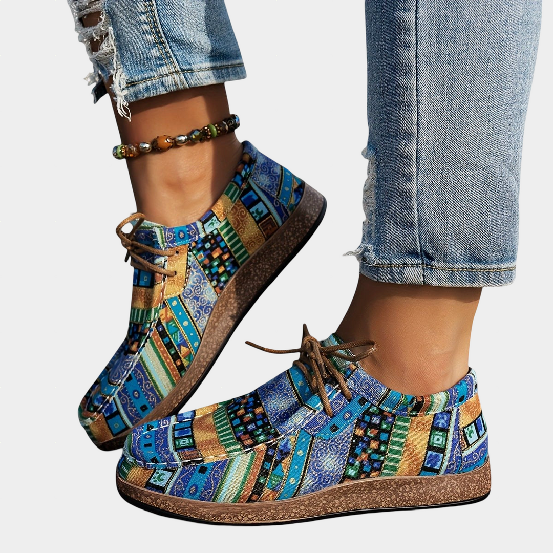 A woman wearing blue boho-print lace-up comfort sneakers while out walking.