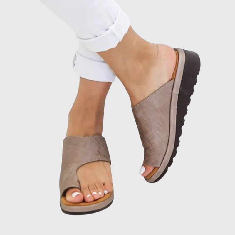 A woman in taupe toe-loop supportive sandals standing gracefully, feet cushioned and at ease.