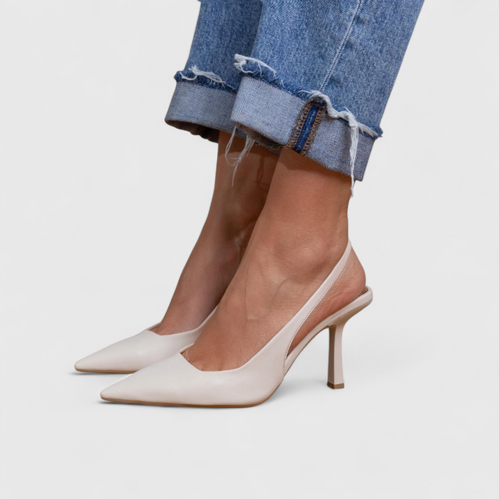 A woman wearing beige pointed slingback stilettos with a slim high heel.