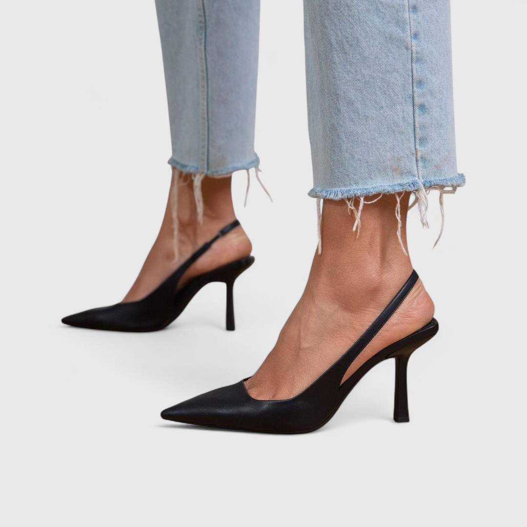 A woman wearing beige pointed slingback stilettos with a slim high heel.
