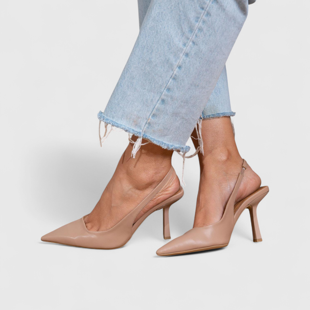 A woman wearing beige pointed slingback stilettos with a slim high heel.