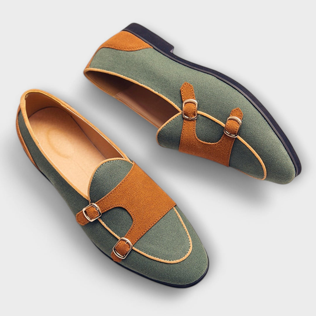 A woman wearing cream and tan round-toe slip-on loafers with twin gold buckle straps, walking with ease.