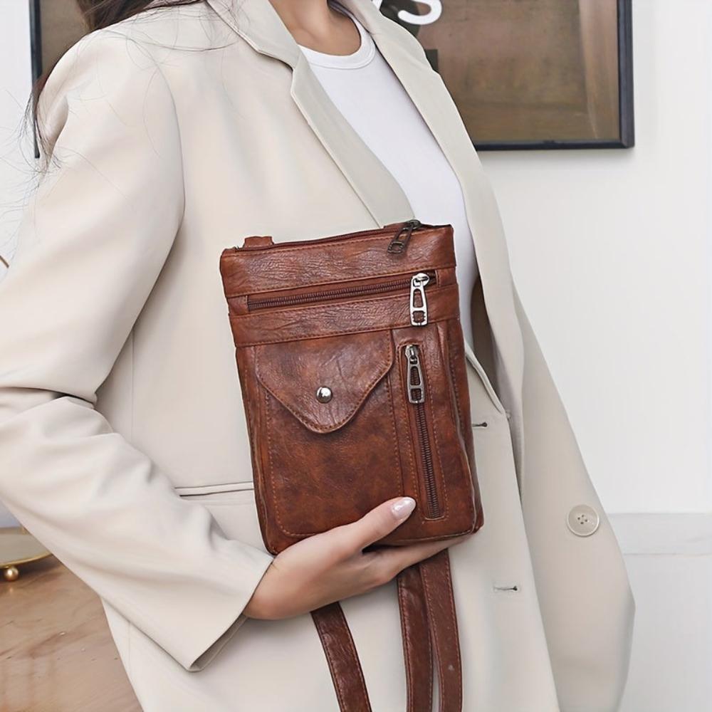A woman wearing a compact vintage crossbody bag across her body while walking through town.