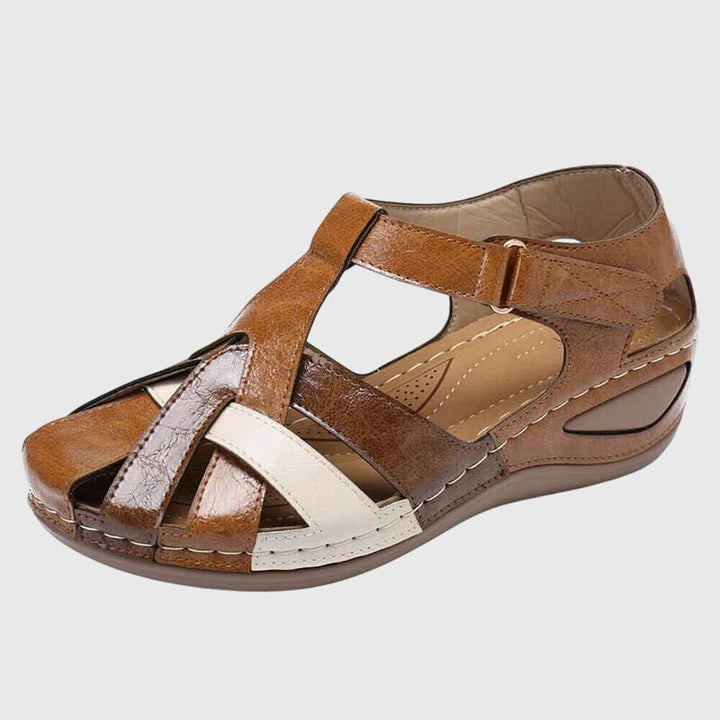 A woman wearing burgundy and brown woven closed-toe wedge sandals with side cutouts, walking with ease