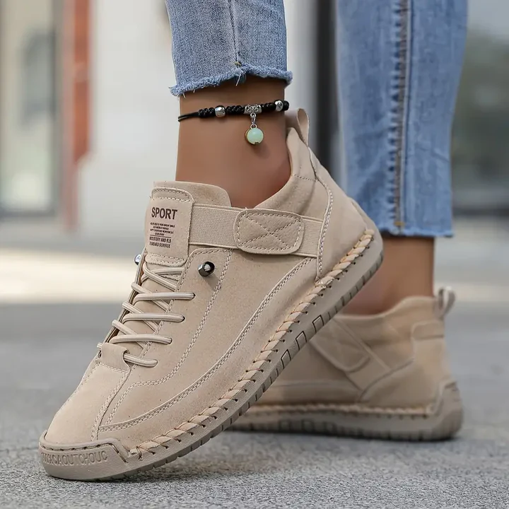 A woman wearing white lace-up orthopaedic sneakers with an adjustable strap.