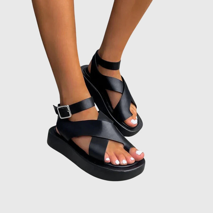 A woman in black chunky platform sandals with an ankle strap, standing confidently, feet cushioned and supported.