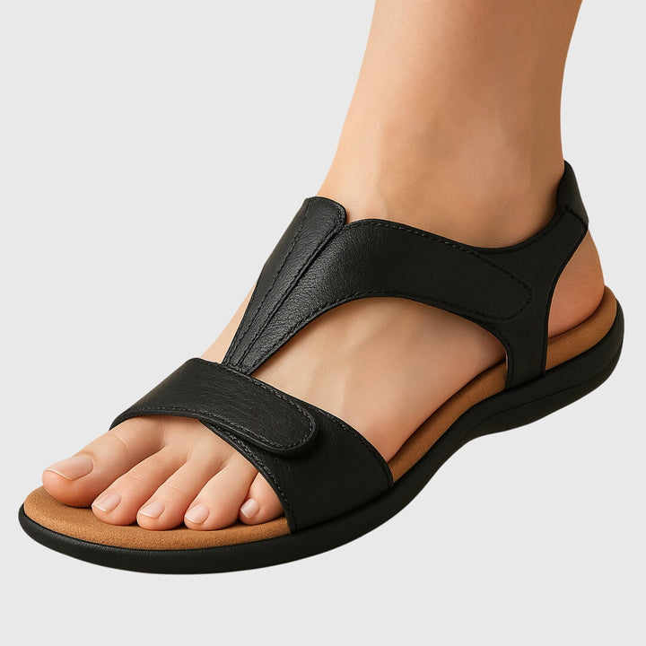 A woman wearing T-strap comfort sandals with a summer dress, looking relaxed and elegant.