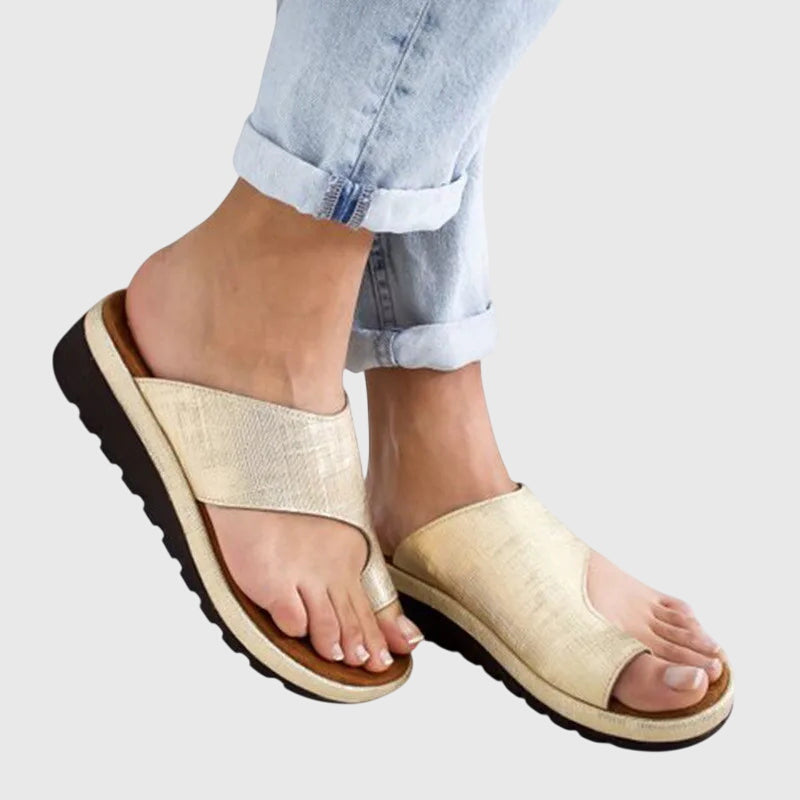 A woman in taupe toe-loop supportive sandals standing gracefully, feet cushioned and at ease.