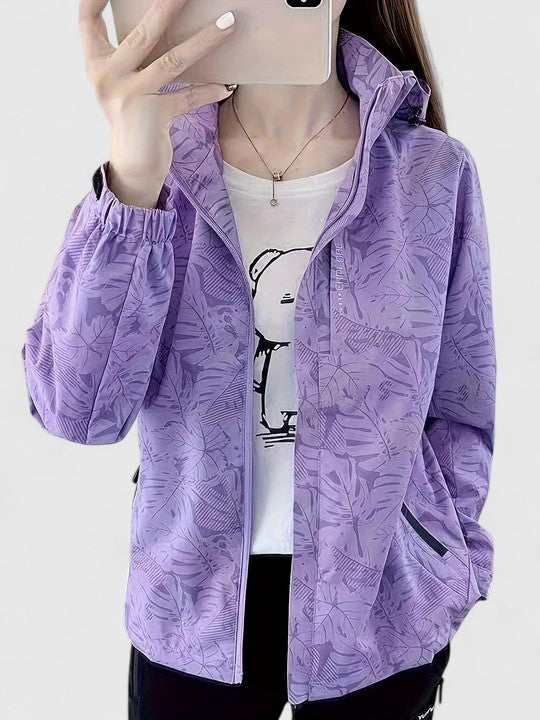 A woman wearing a botanical leaf-print jacket with a hood outdoors