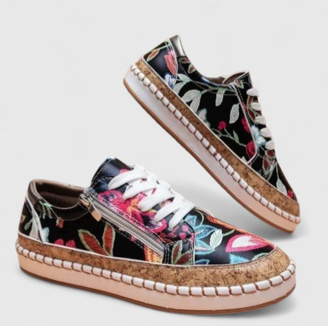 A woman wearing floral lace-up orthopaedic sneakers with a side zip and platform sole.
