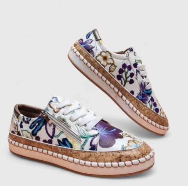A woman wearing floral lace-up orthopaedic sneakers with a side zip and platform sole.