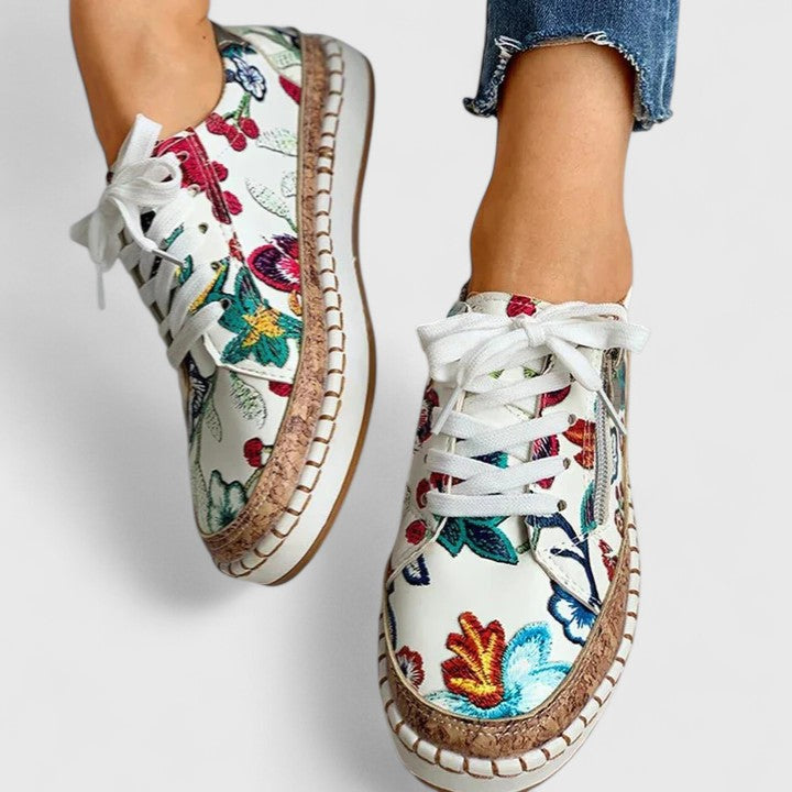 A woman wearing floral lace-up orthopaedic sneakers with a side zip and platform sole.