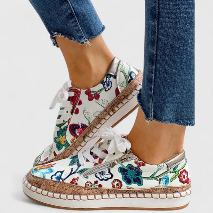 A woman wearing floral lace-up orthopaedic sneakers with a side zip and platform sole.
