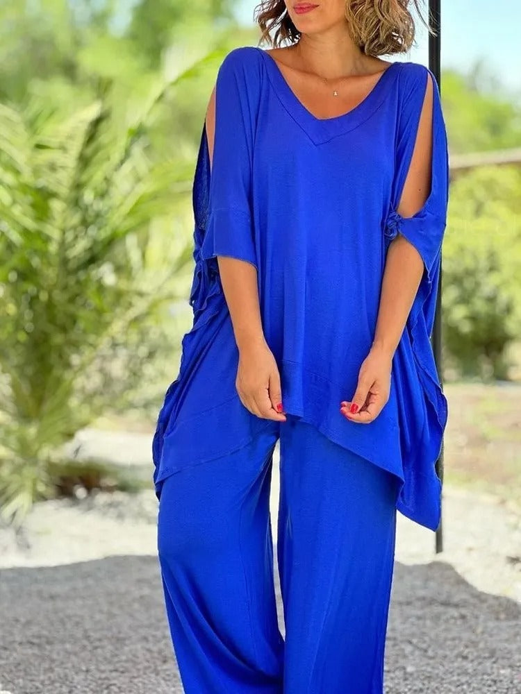 A woman wearing a draped top with shoulder cut-out details and matching wide pants.