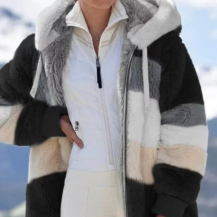 A woman wearing a plush oversized hooded zip jacket in blue and cream colour-block panels.