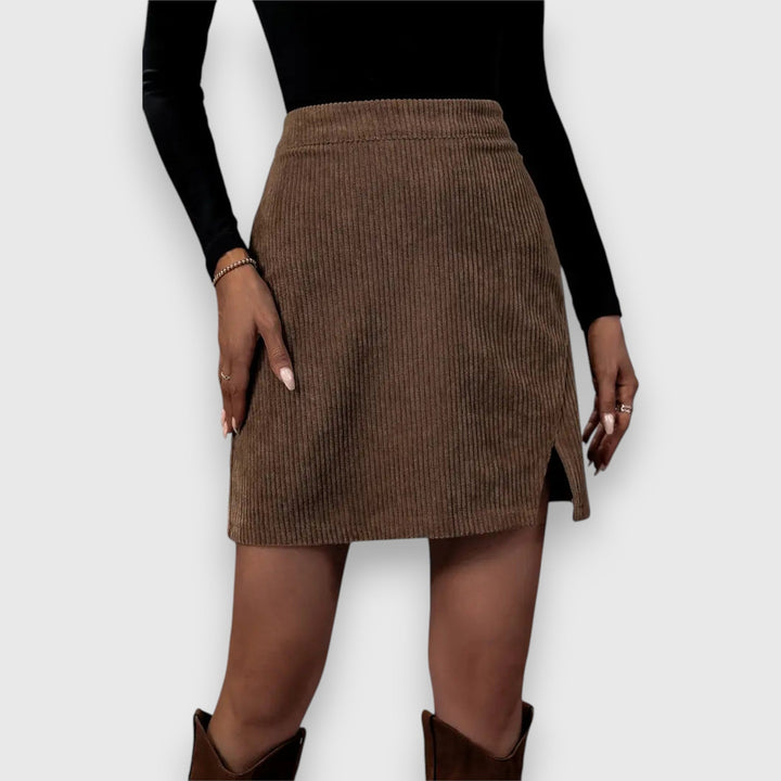 A woman in a textured ribbed skirt with a front slit, styled with a sweater for a relaxed fall look.
