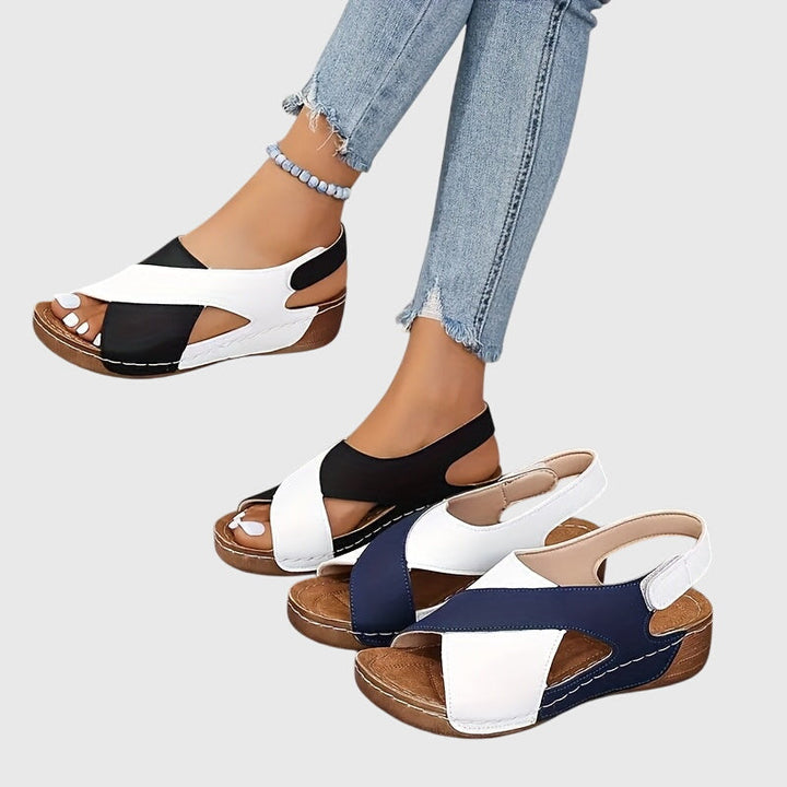 A woman wearing navy cross-strap sandals with a cushioned insole and secure heel fastening.