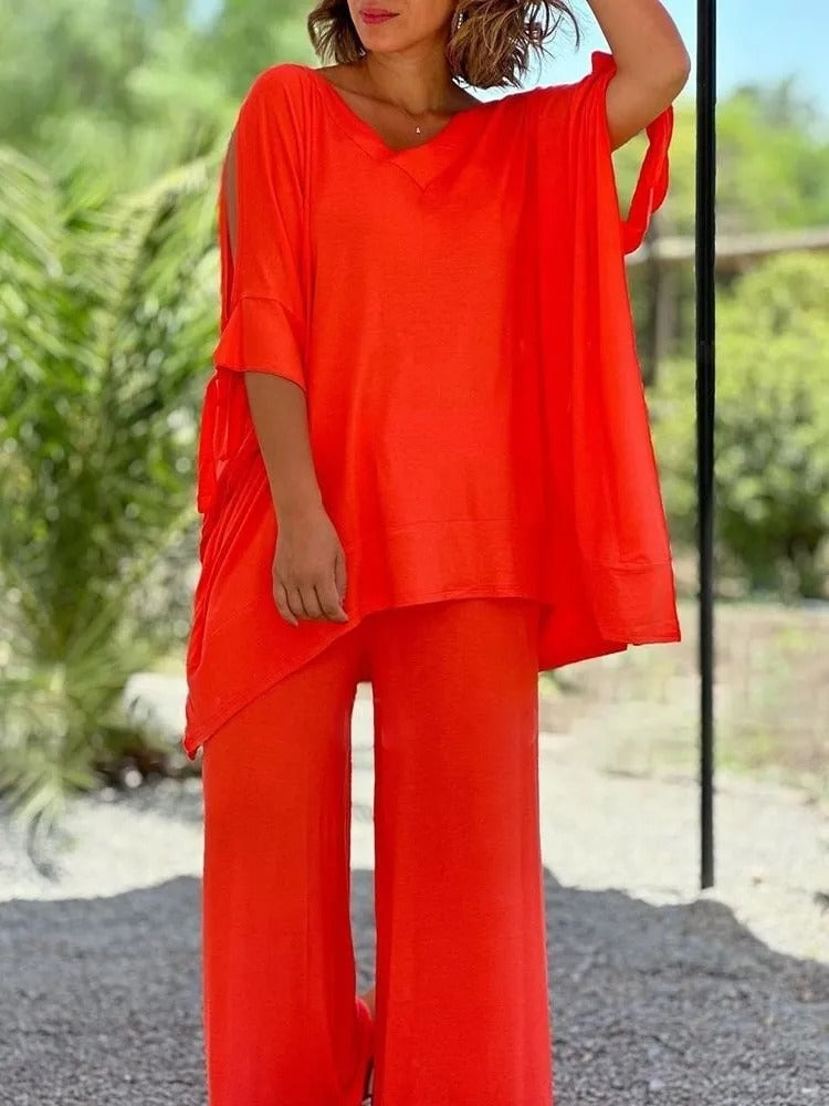 A woman wearing a draped top with shoulder cut-out details and matching wide pants.