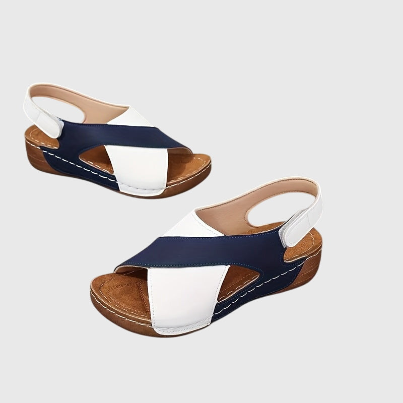 A woman wearing navy cross-strap sandals with a cushioned insole and secure heel fastening.