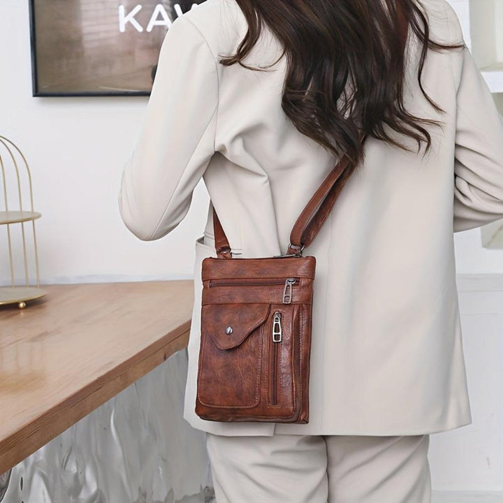 A woman wearing a compact vintage crossbody bag across her body while walking through town.