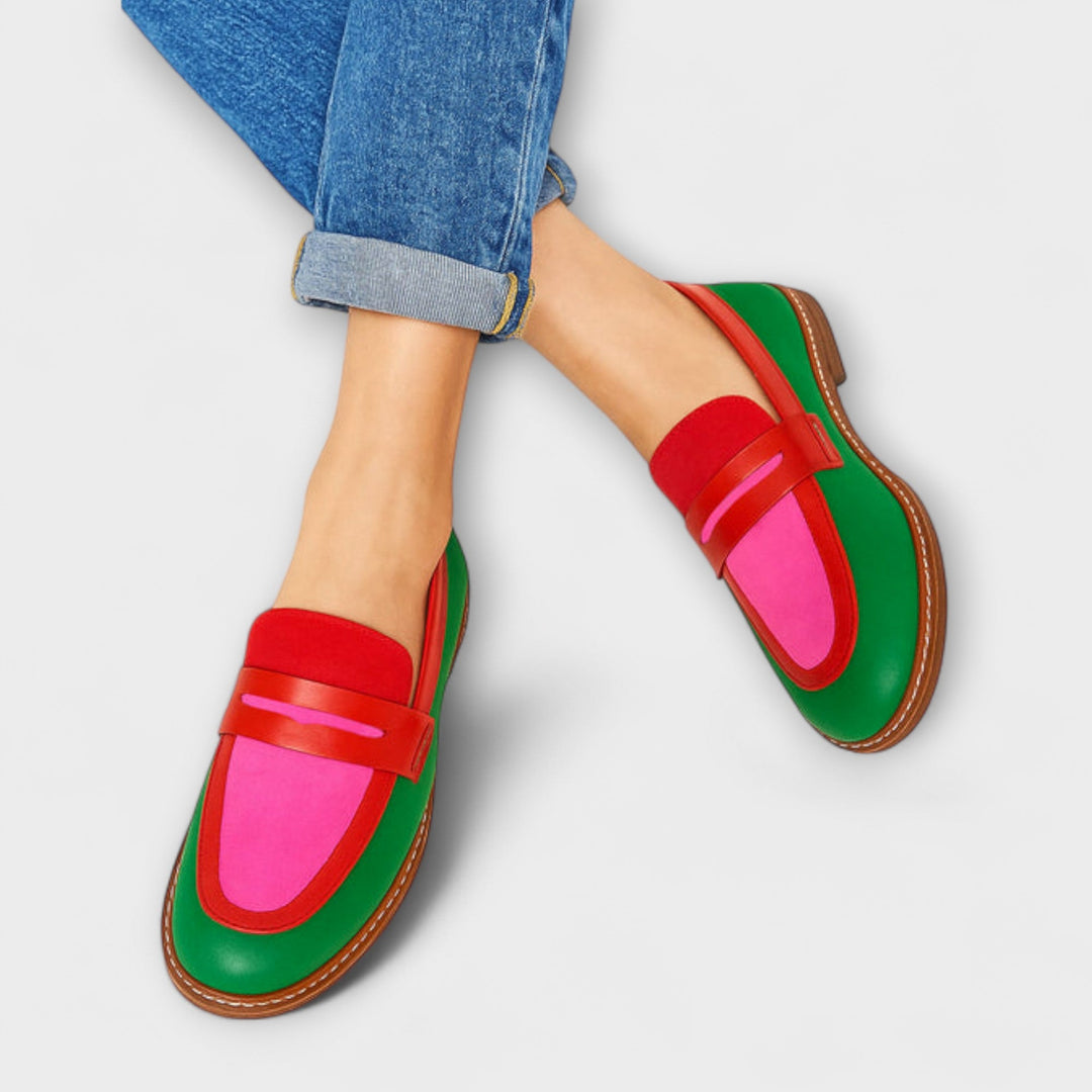 A woman in casual contrast loafers walking through a bright town street.