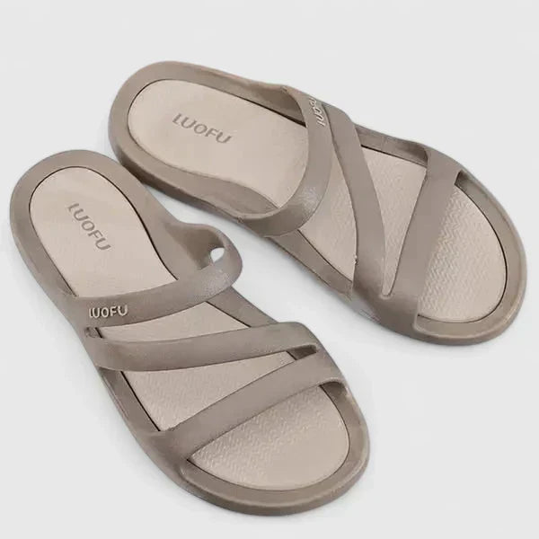A woman walking confidently outdoors in supportive, cushioned orthopaedic sandals.