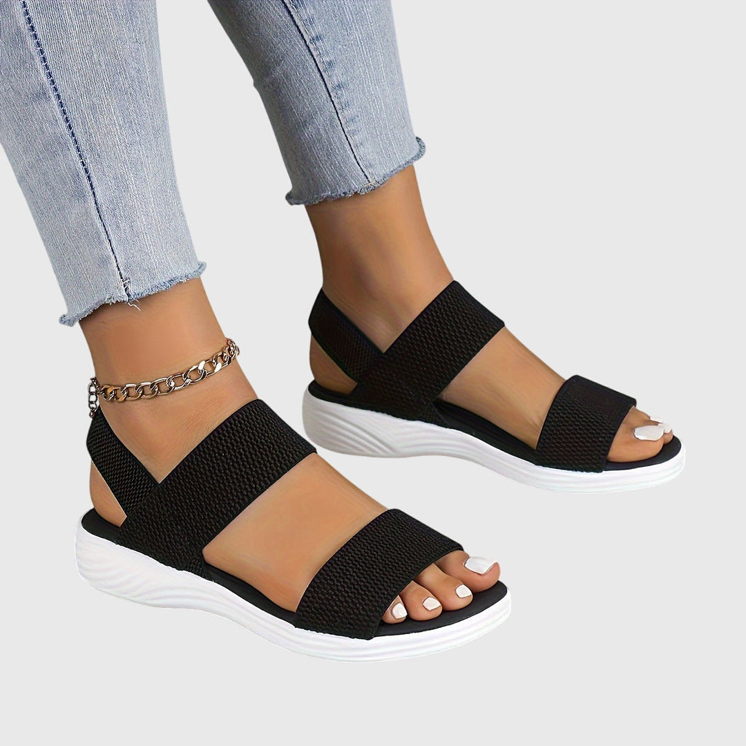 Black open-toe everyday sandals with wide stretch straps and a thick cushioned sole.