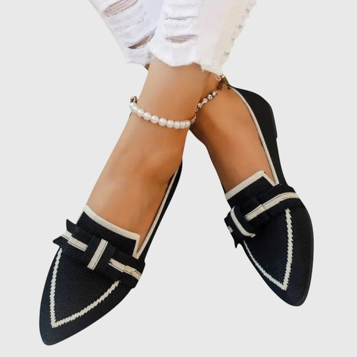 A woman wearing black flat loafers with a chic bow detail, styled for an easy day out.