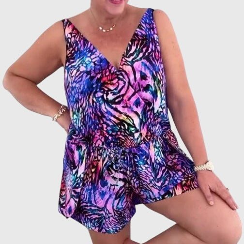 A woman in a blue printed swim playsuit with a flowing top and shorts, relaxed by the pool.