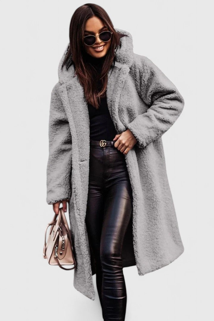 A woman wearing a long, softly textured hooded winter coat with an open front